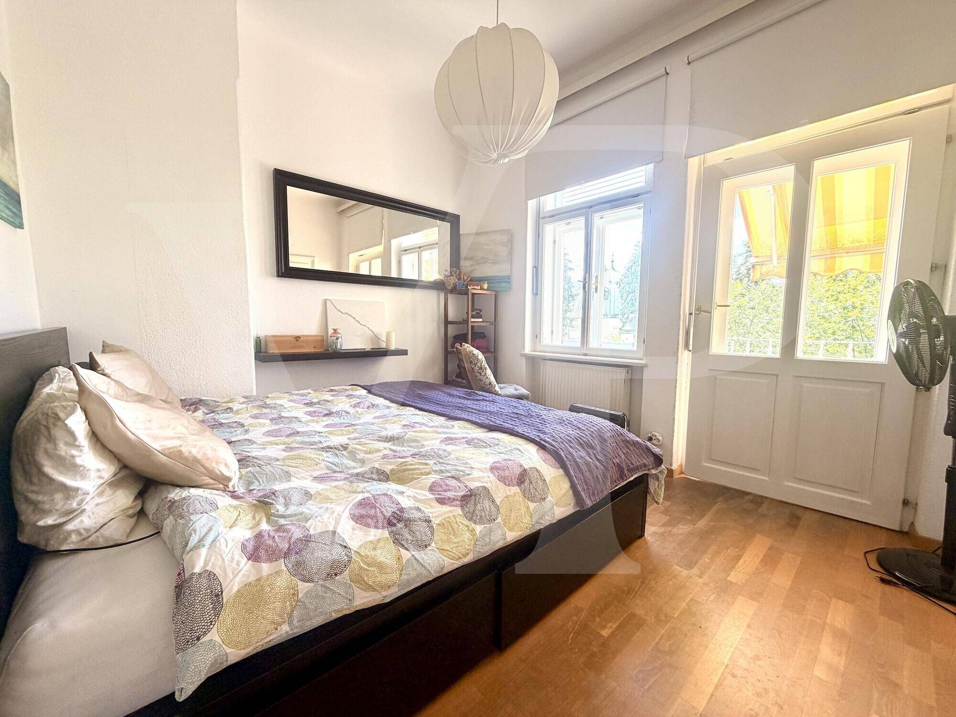Gemütliches Schlafzimmer mit Doppelbett, Fenster und Zugang zu einem französischen Balkon.