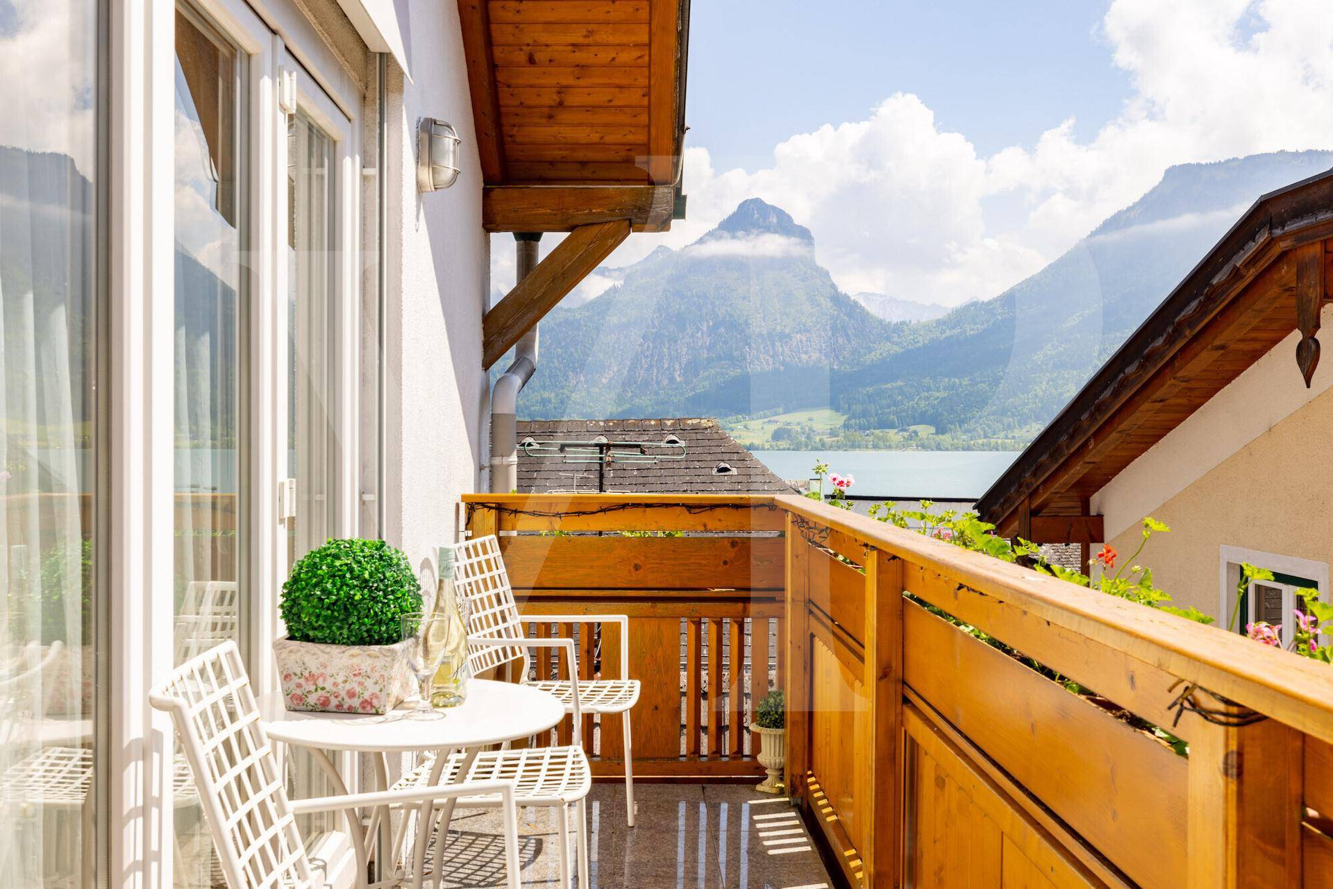 Sonniger Balkon mit Sitzgelegenheiten und einem atemberaubenden Blick auf den See und die Berge.