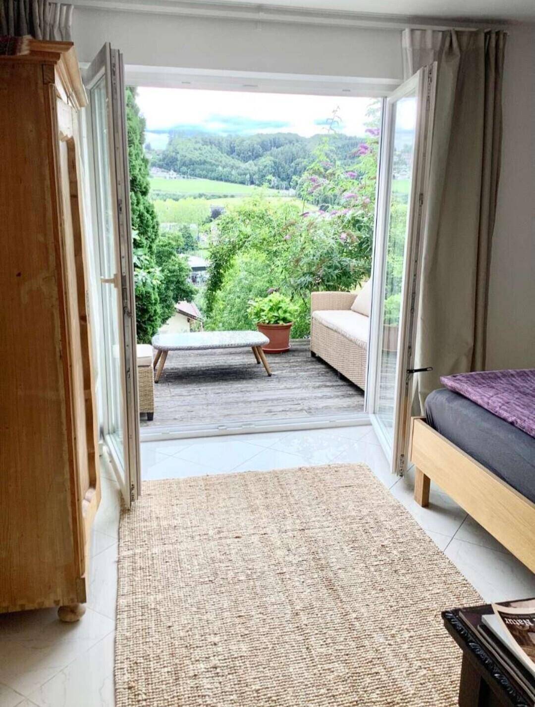 Schlafzimmer mit direktem Zugang zu einer Terrasse und idyllischem Blick ins Grüne.