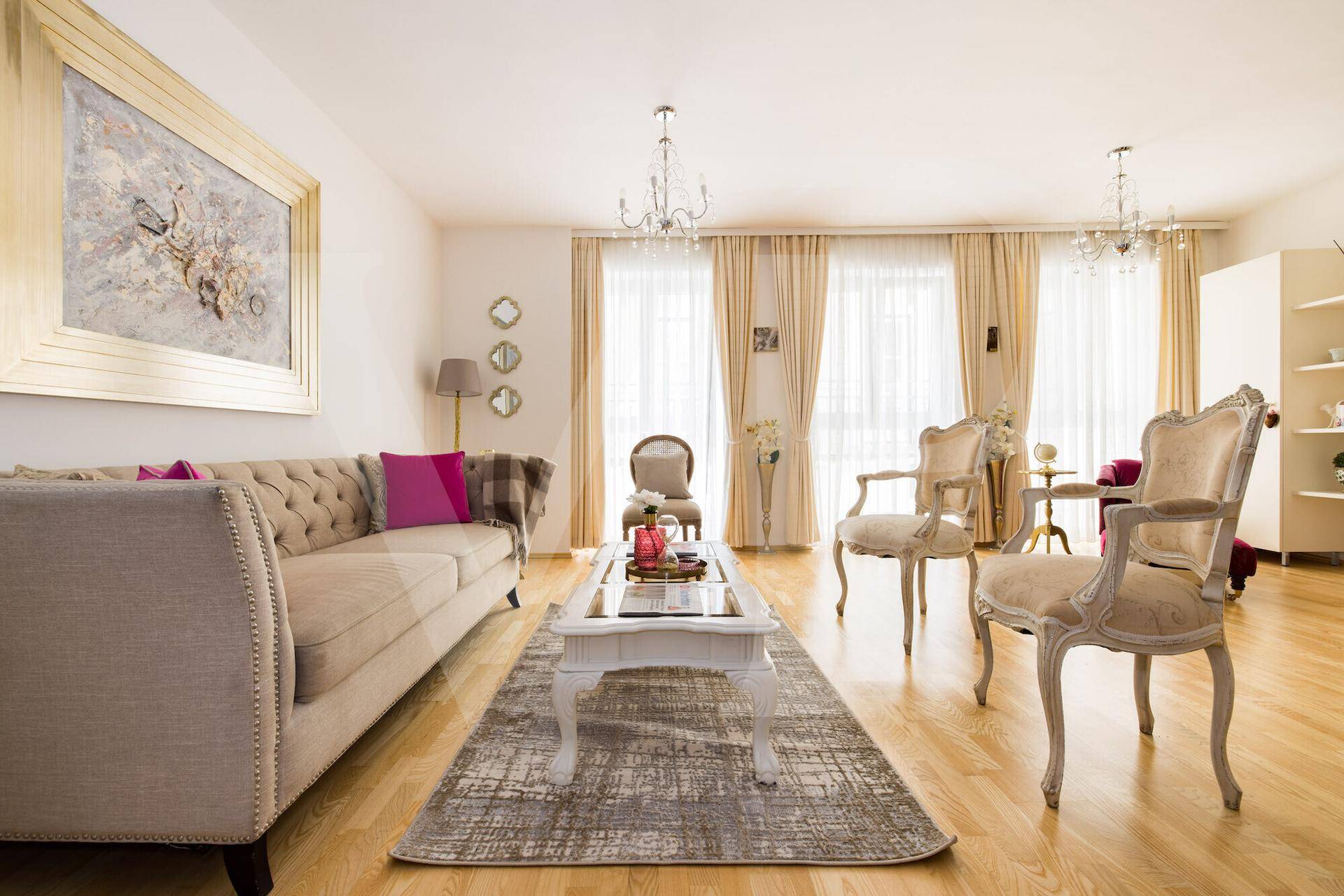 Elegantes Wohnzimmer mit beigem Sofa, Holzboden und klassischen Möbeln, beleuchtet durch Kronleuchter.