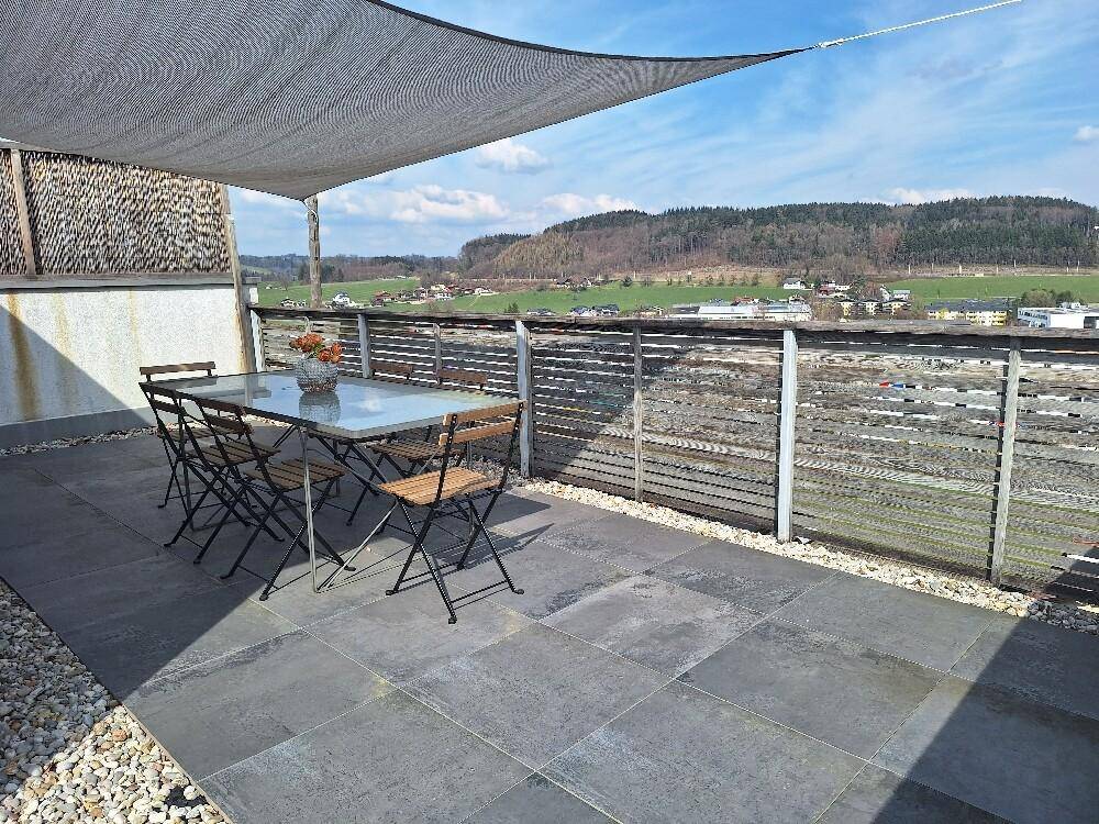Große Sonnenterrasse mit Esstisch, Stühlen und weitem Panoramablick über die Landschaft.