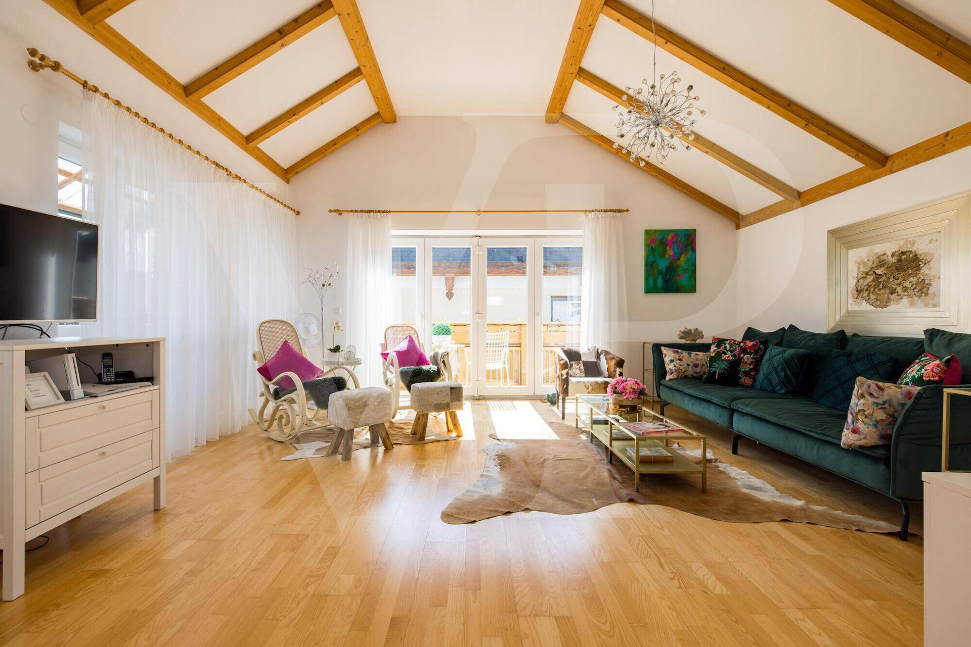 Gemütliches Wohnzimmer mit grünem Sofa, Holzboden und hohen Decken mit sichtbaren Holzbalken.