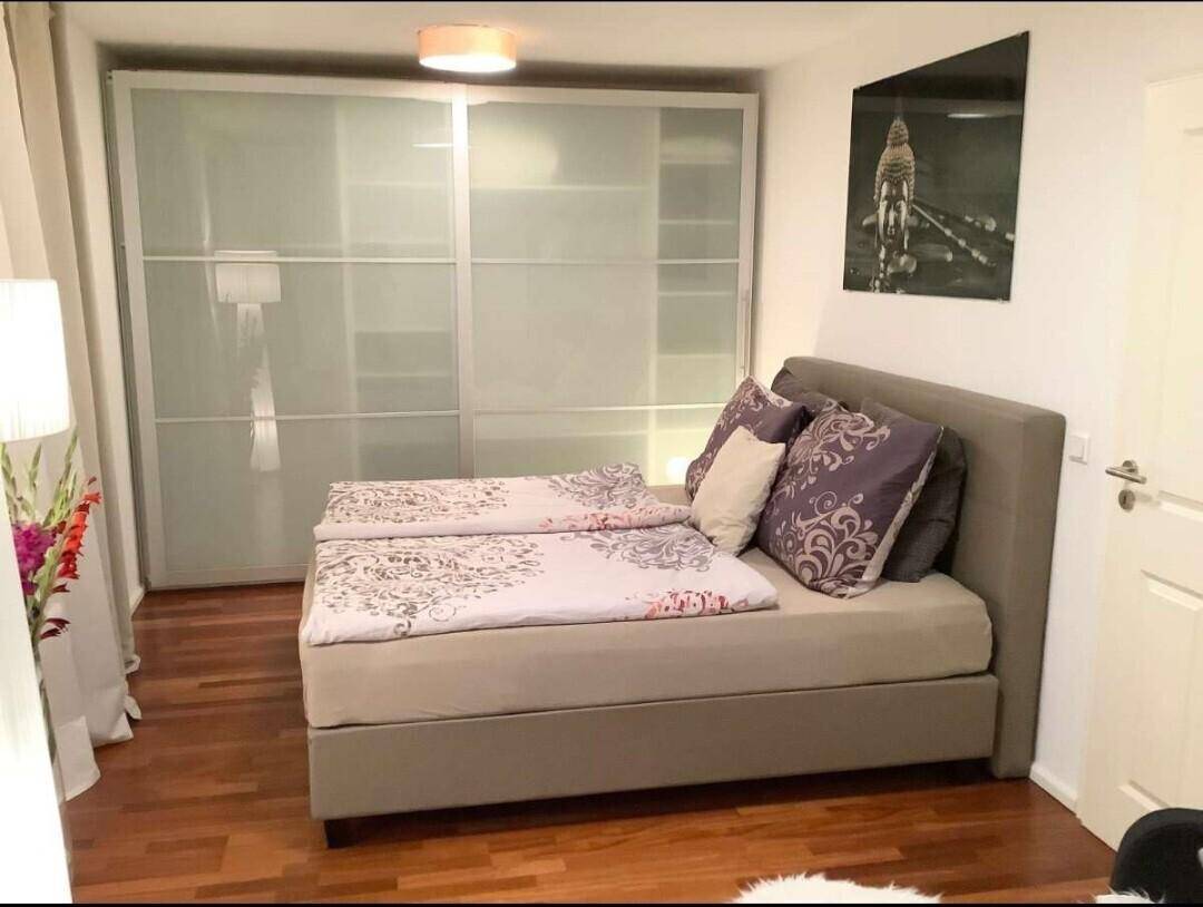 Schlafzimmer mit Doppelbett und großem Einbauschrank mit Milchglasfronten.