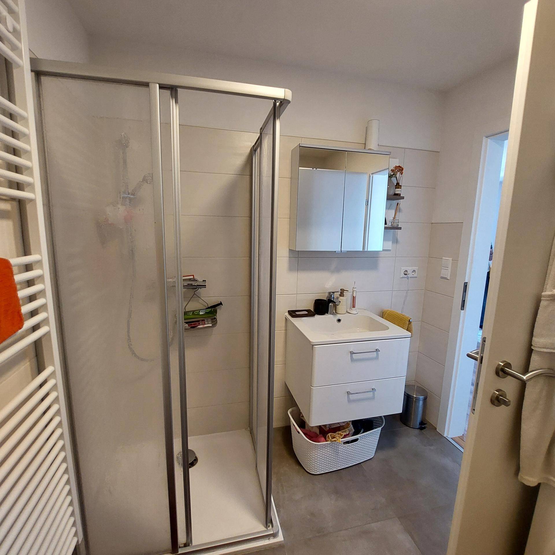 Modernes Badezimmer mit Duschkabine, Einzelwaschbecken und beheiztem Handtuchhalter.