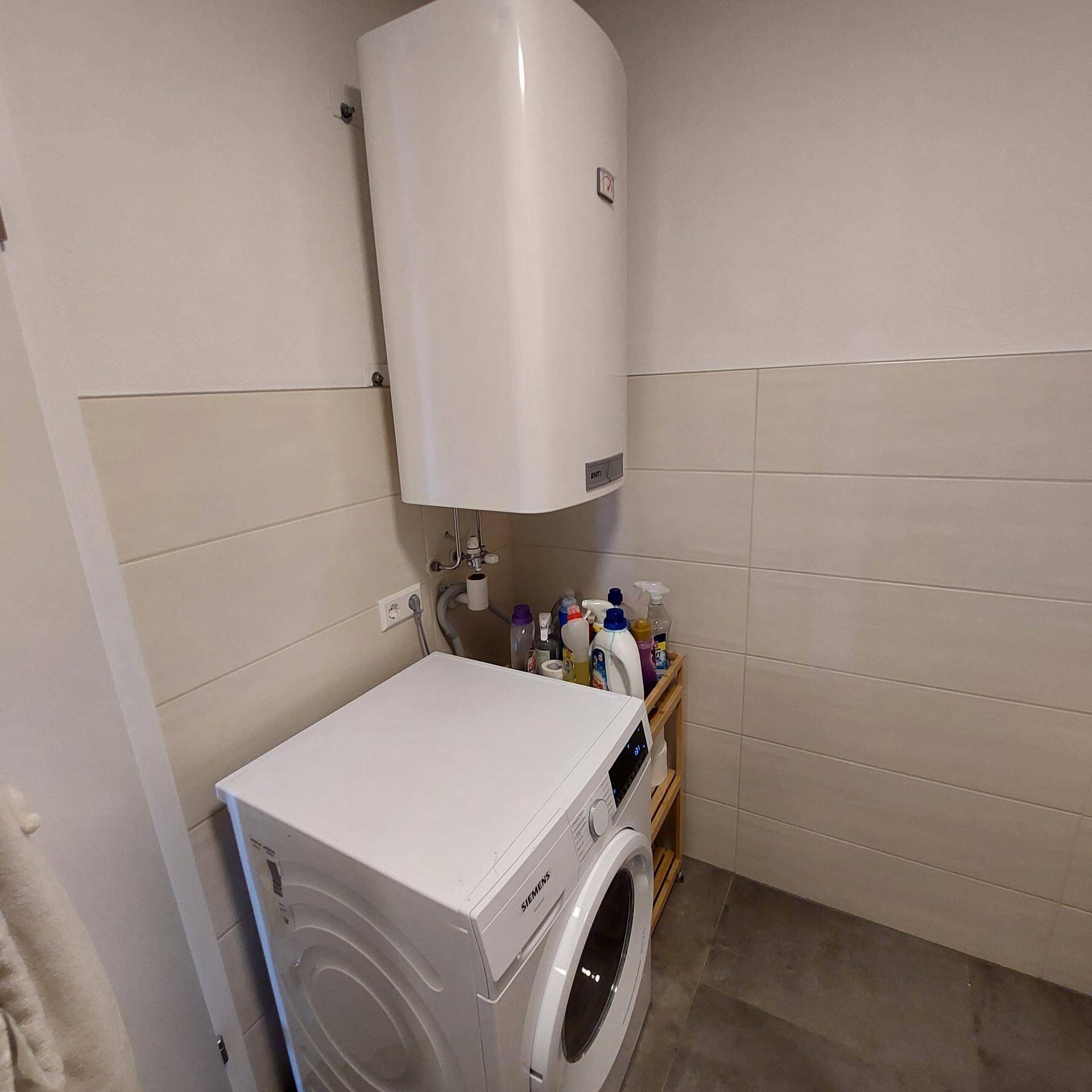 Praktischer Hauswirtschaftsraum mit Waschmaschine und Warmwasserboiler.