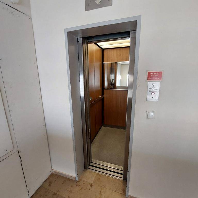 Geräumiger Aufzug mit Holzverkleidung im Treppenhaus des Gebäudes.