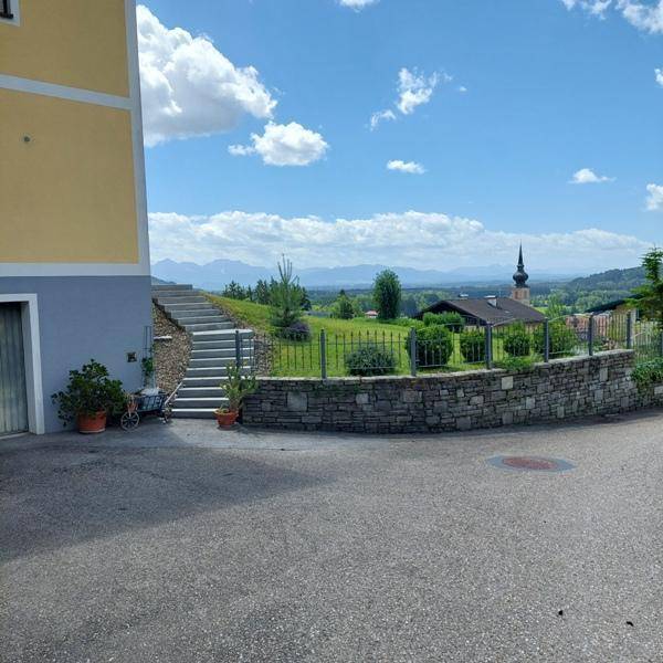 Blick auf die Seitenfassade des Hauses mit Steintreppe und weitem Ausblick auf die Landschaft und Berge.