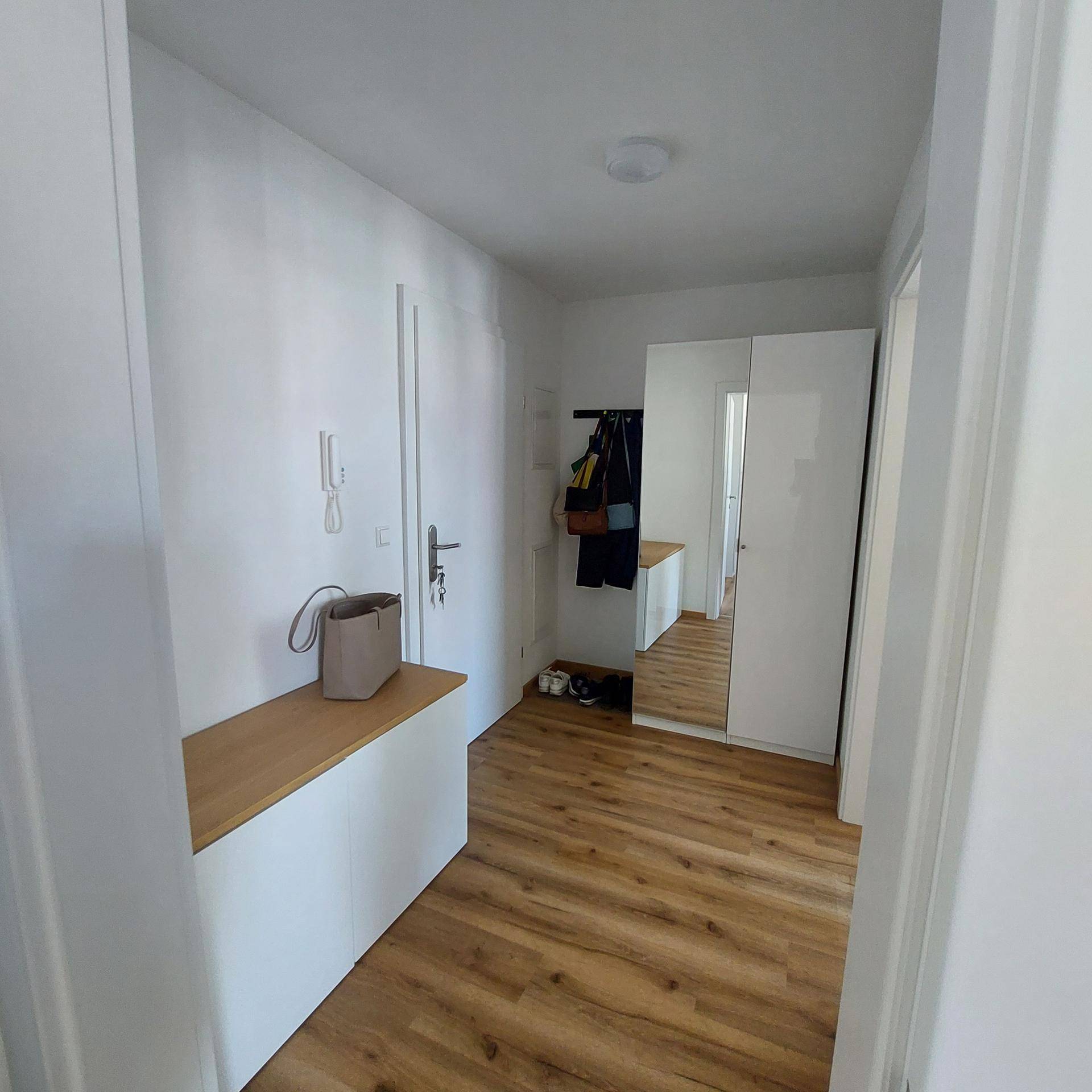 Heller Eingangsbereich mit Garderobe, Spiegel und praktischer Sitzbank.