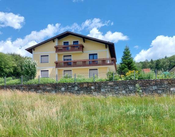 Das gelbe Wohnhaus präsentiert sich mit zwei Balkonen und einem gepflegten Gartenbereich.