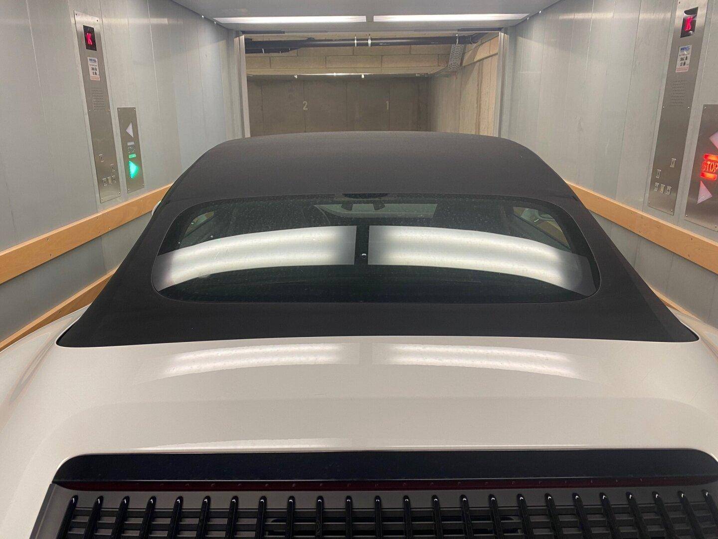 Blick auf das Heck eines Sportwagens im Inneren des Autoaufzugs mit seitlichen Schutzleisten.