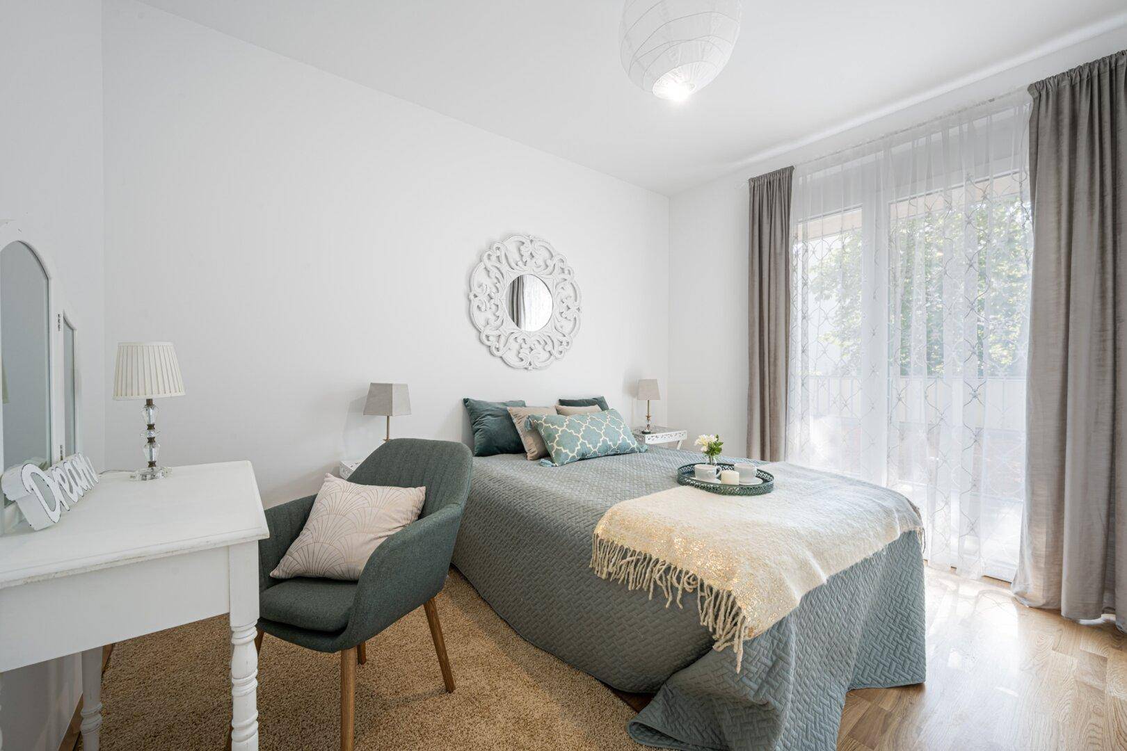 Helles Schlafzimmer mit Holzboden, einem Doppelbett und direktem Zugang zu einem Balkon.