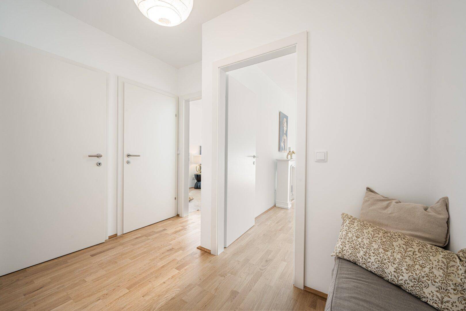 Heller Flur mit Holzboden und weißen Türen, der zu weiteren Räumen führt.