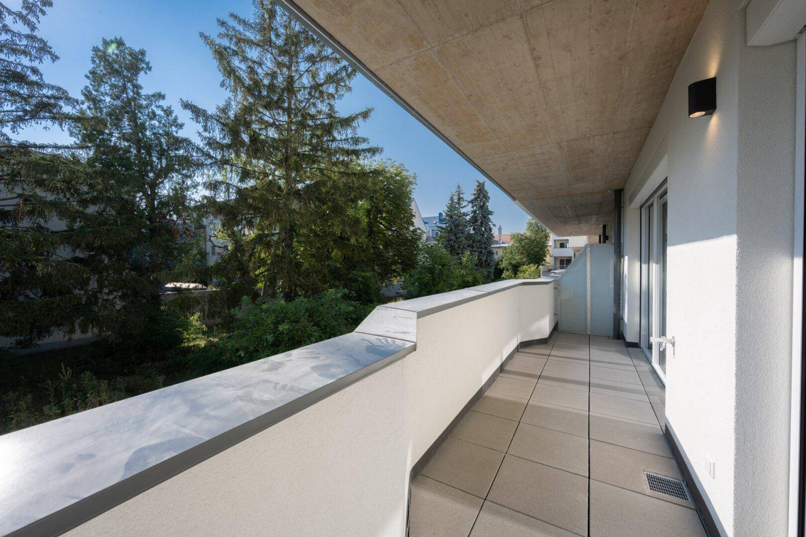 Langer Balkon mit Fliesenboden und Blick ins Grüne, ideal zum Entspannen.