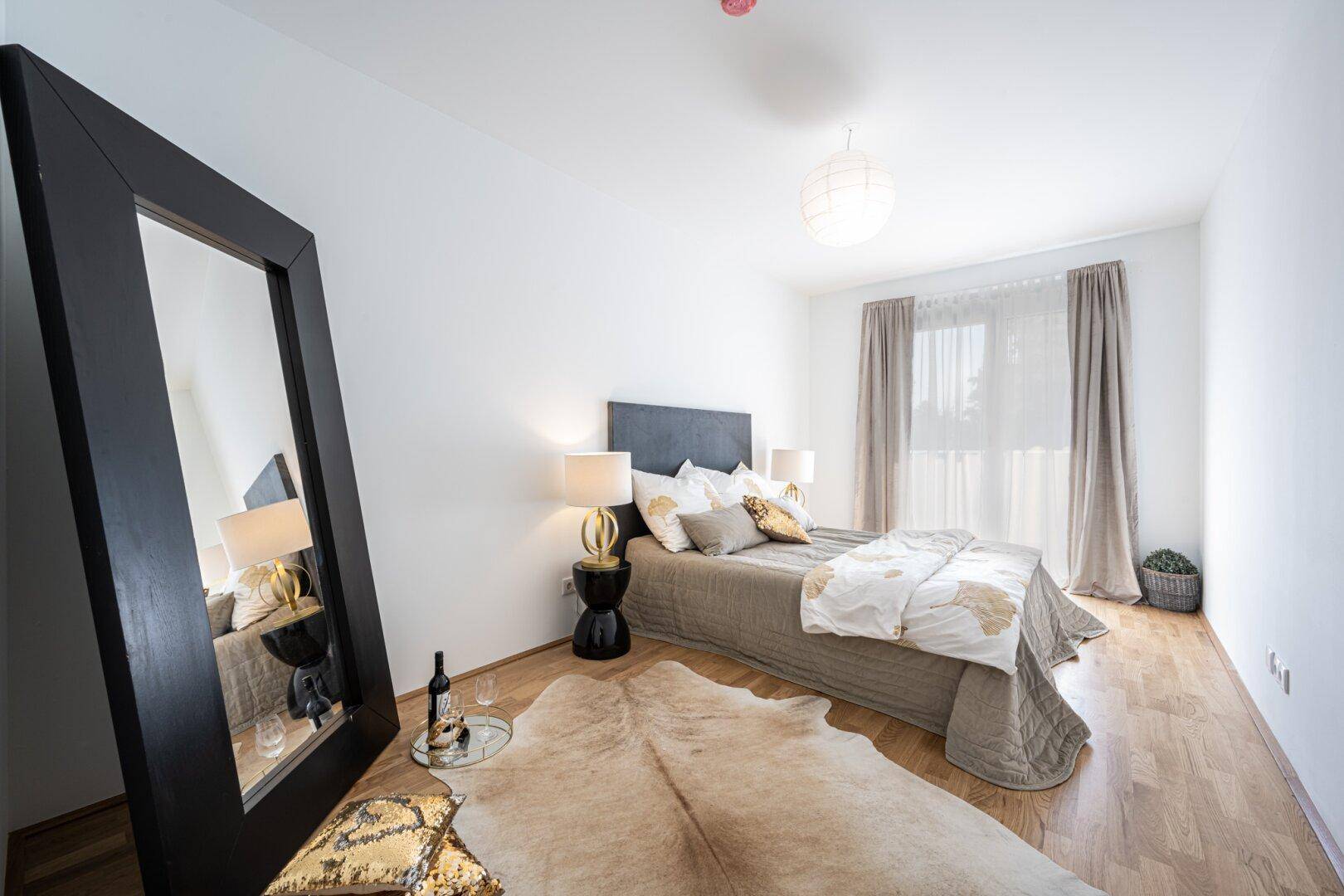 Geräumiges Schlafzimmer mit Doppelbett, Holzboden und großem Spiegel.