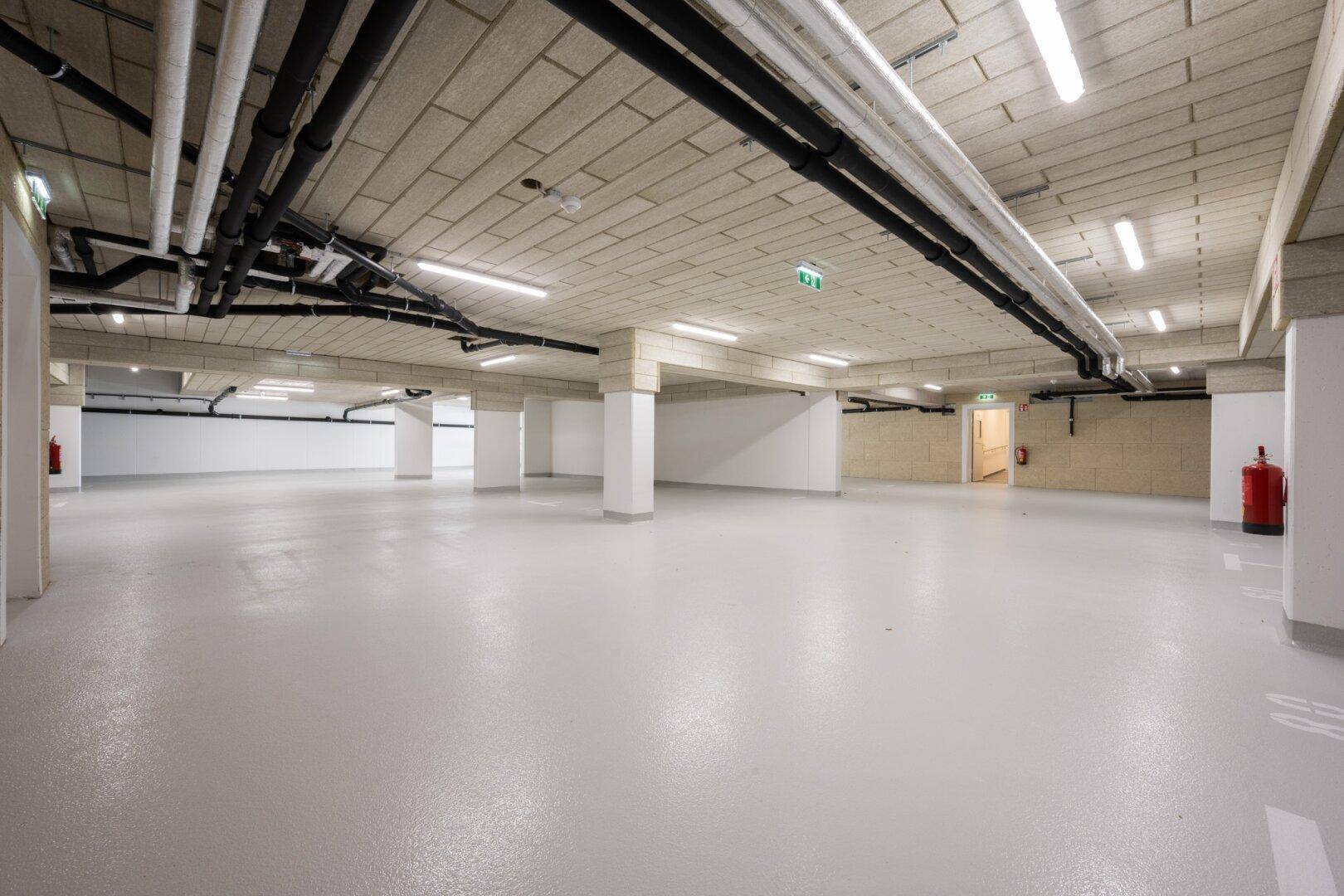 Geräumige Tiefgarage mit vielen Stellplätzen und moderner Beleuchtung, gut beleuchtet.