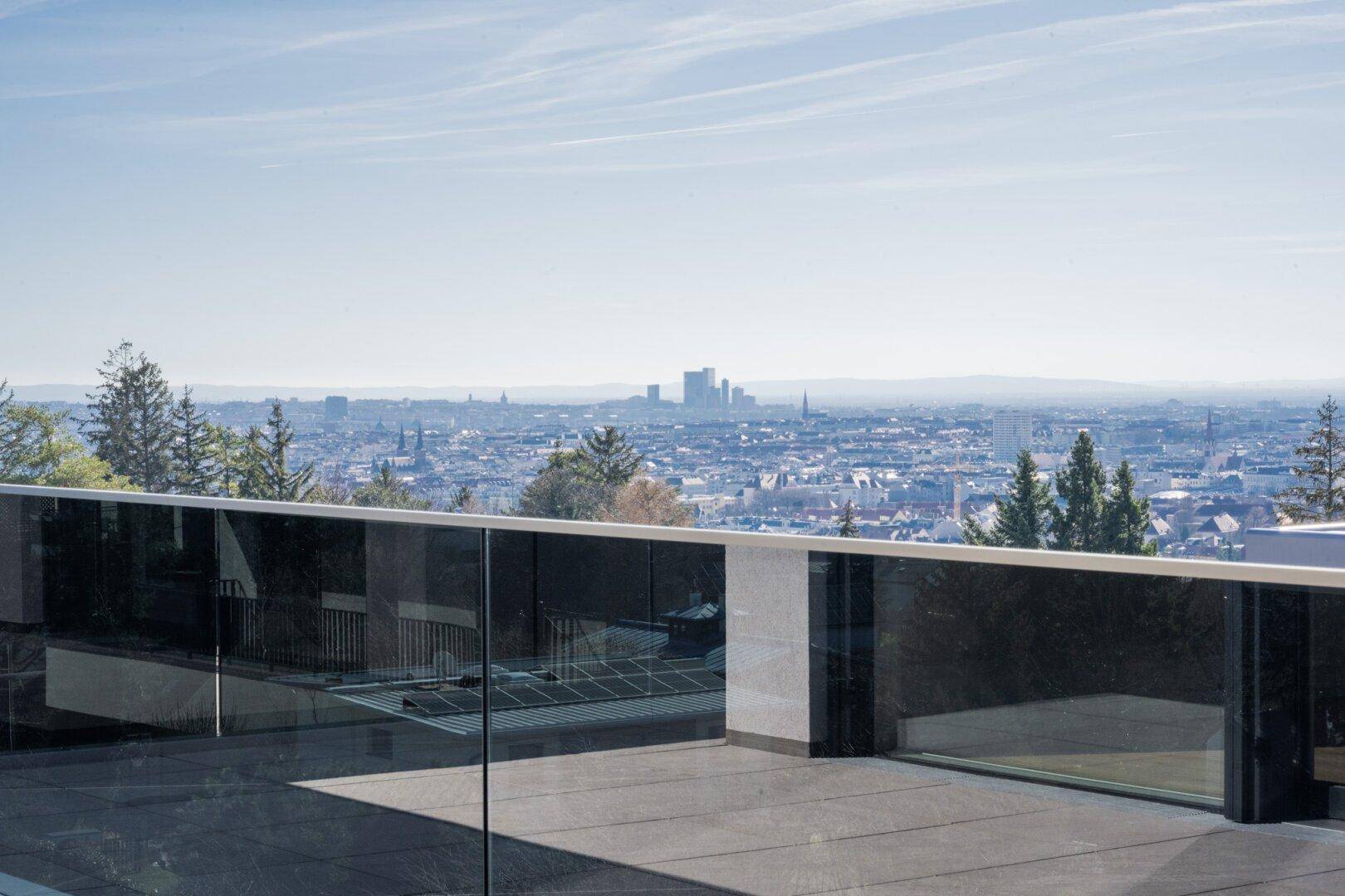 Große Dachterrasse mit Glasgeländer und beeindruckendem Panoramablick über die Stadt.
