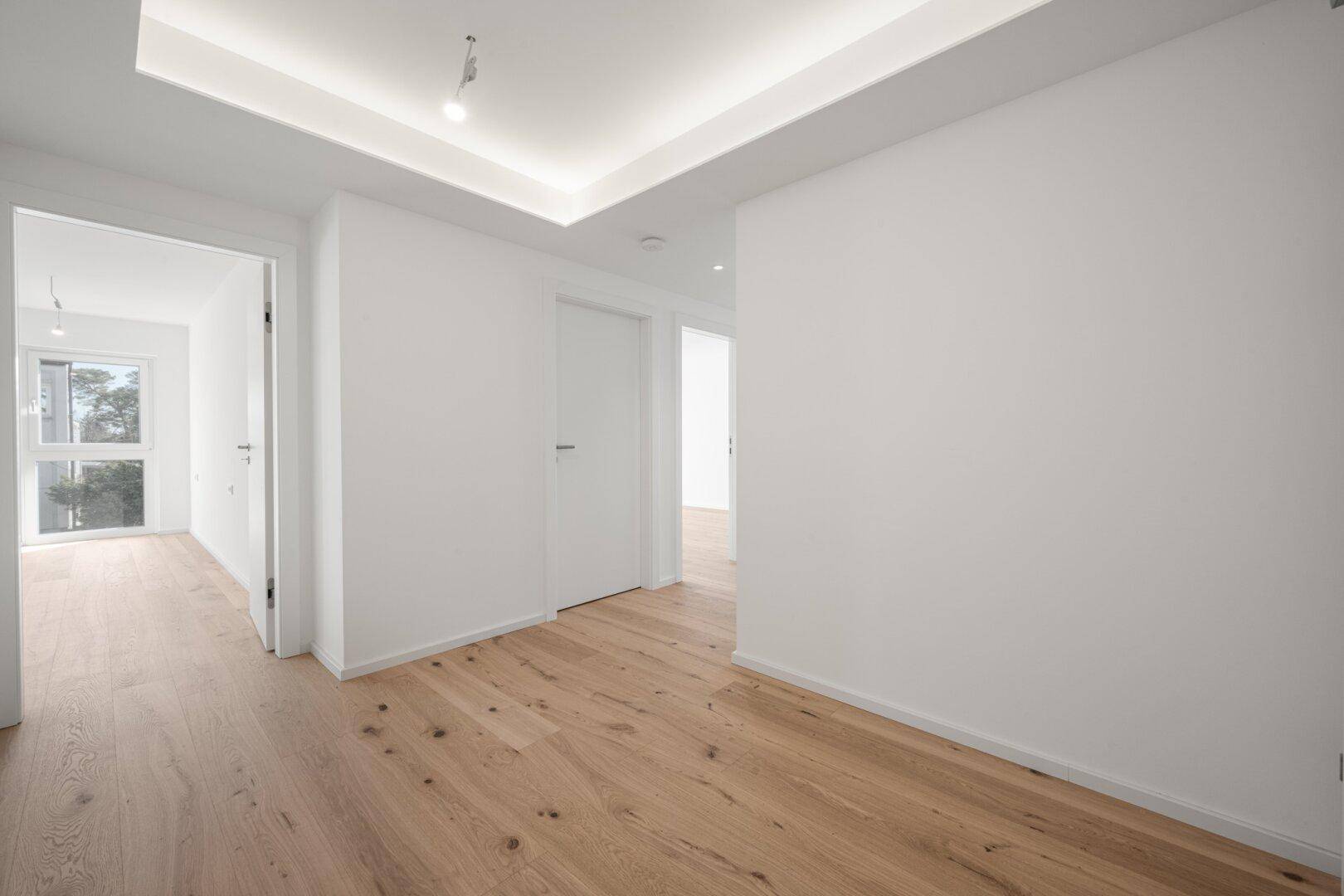 Moderner Flur mit indirekter Deckenbeleuchtung und hellem Holzboden.