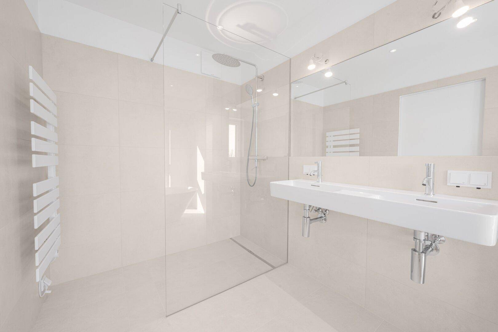 Modernes Badezimmer mit großer begehbarer Dusche, Doppelwaschbecken und beheiztem Handtuchhalter.