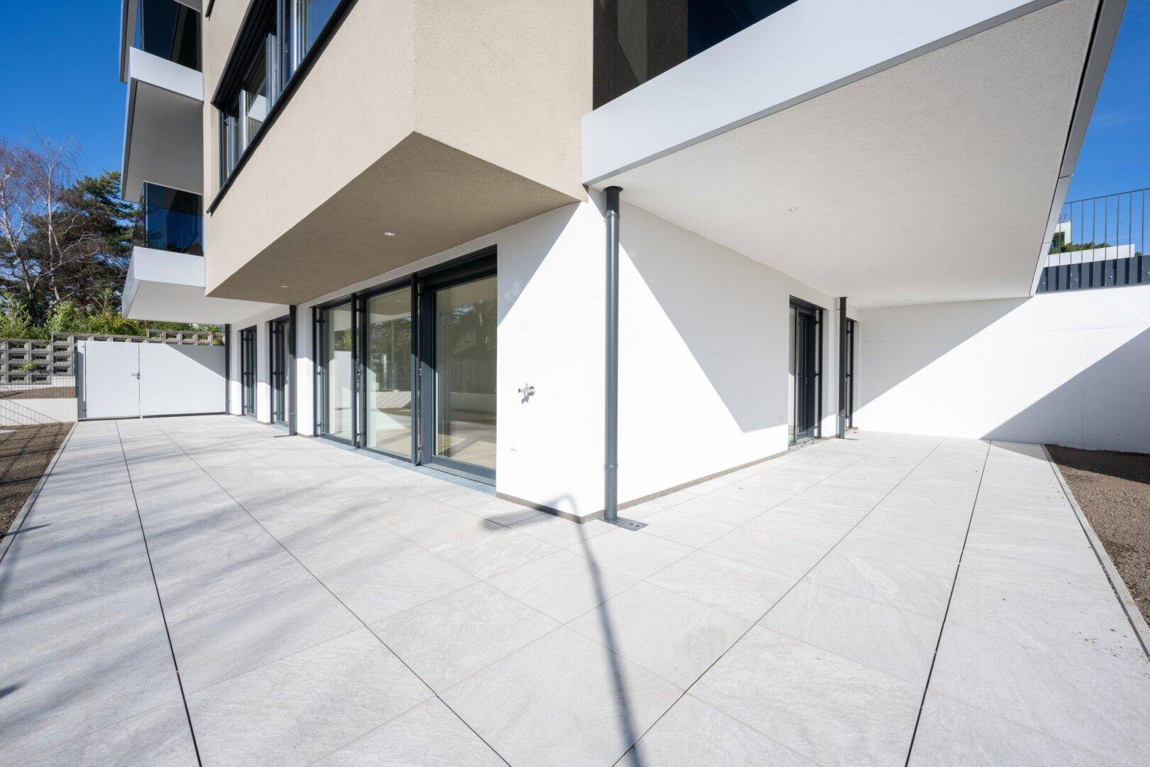 Große, geflieste Terrasse im Erdgeschoss mit Zugang zu mehreren Räumen des Gebäudes.