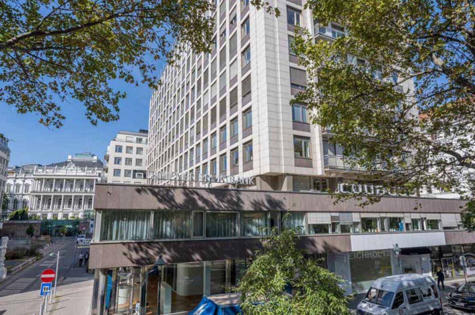 Hohes Gebäude mit vielen Fenstern und moderner Architektur in einer städtischen Umgebung.