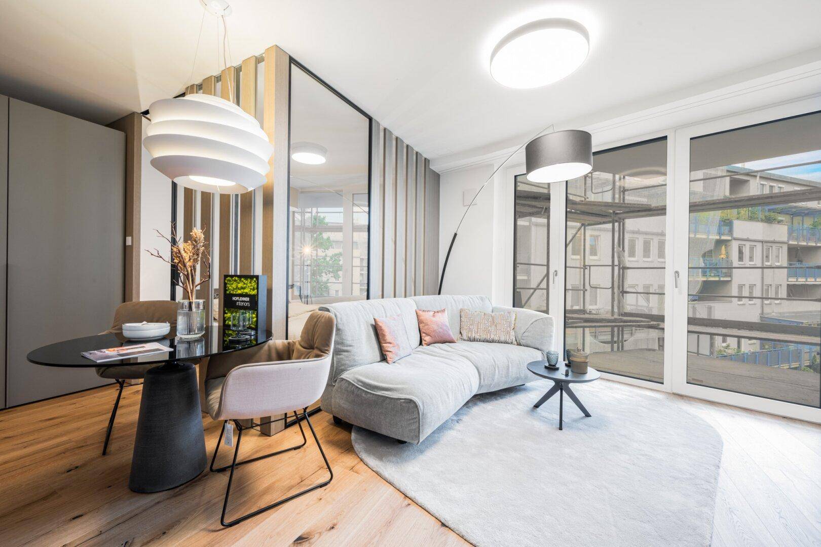 Stilvoller Wohn- und Essbereich mit bequemer Couch, modernem Esstisch und großen Fenstern.