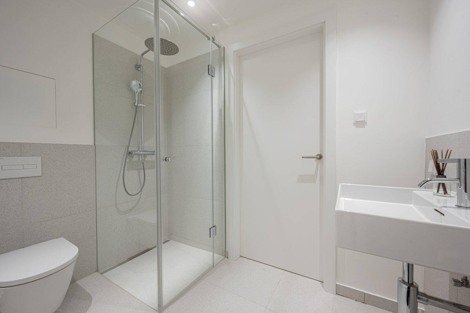 Modernes Badezimmer mit ebenerdiger Dusche, wandhängendem WC und eleganten Fliesen.