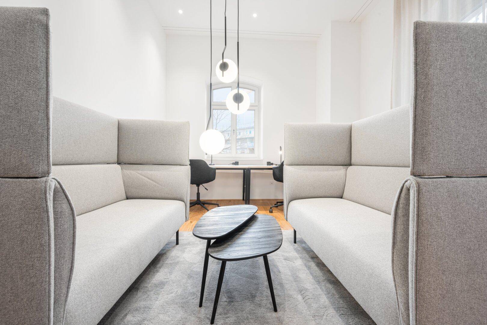 Modernes Büro mit ergonomischen Sitzgelegenheiten, Teppichboden und großen Fenstern für Tageslicht.