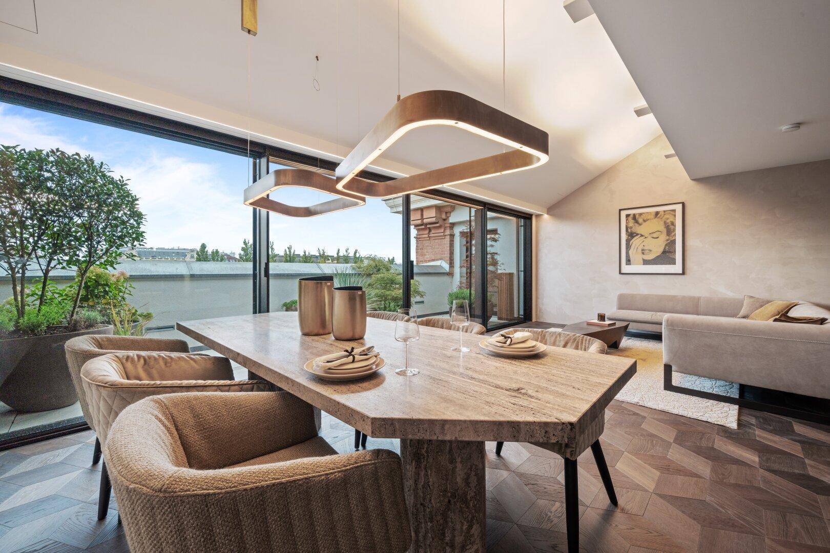 Geräumiger Essbereich mit großformatigem Steintisch, Holzboden und Zugang zur Dachterrasse.