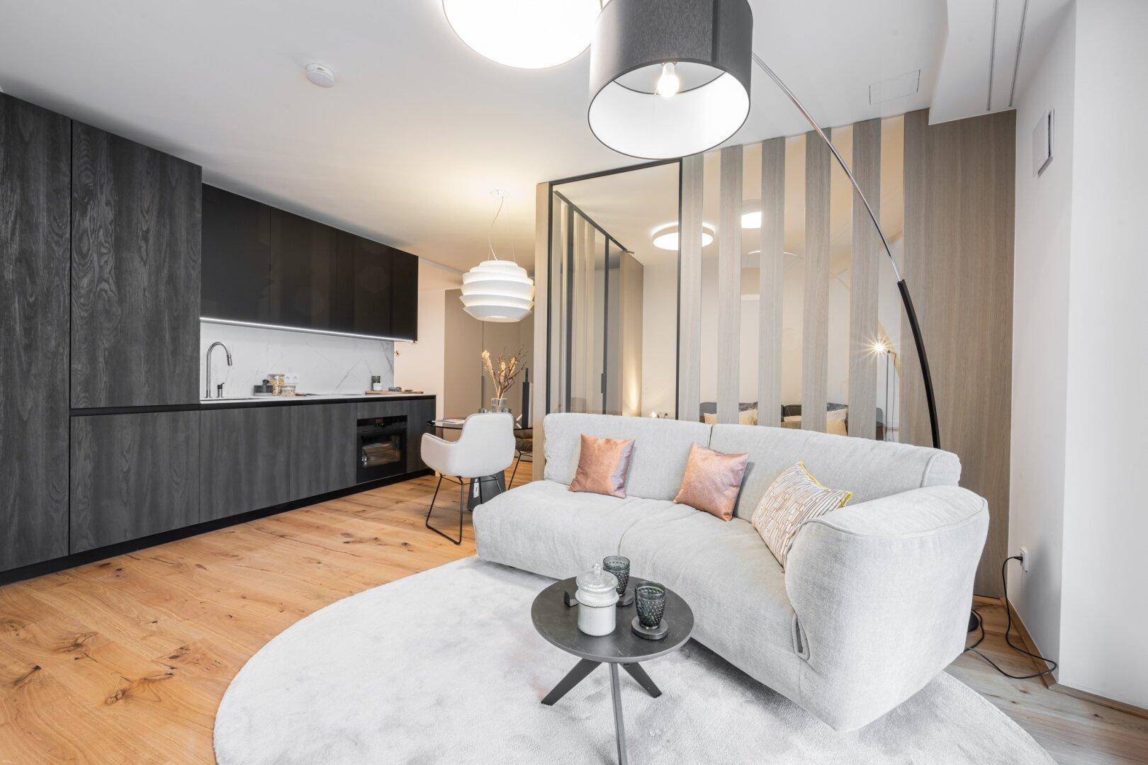 Moderner Wohnbereich mit Holzboden, bequemer Couch und integrierter Küchenzeile.