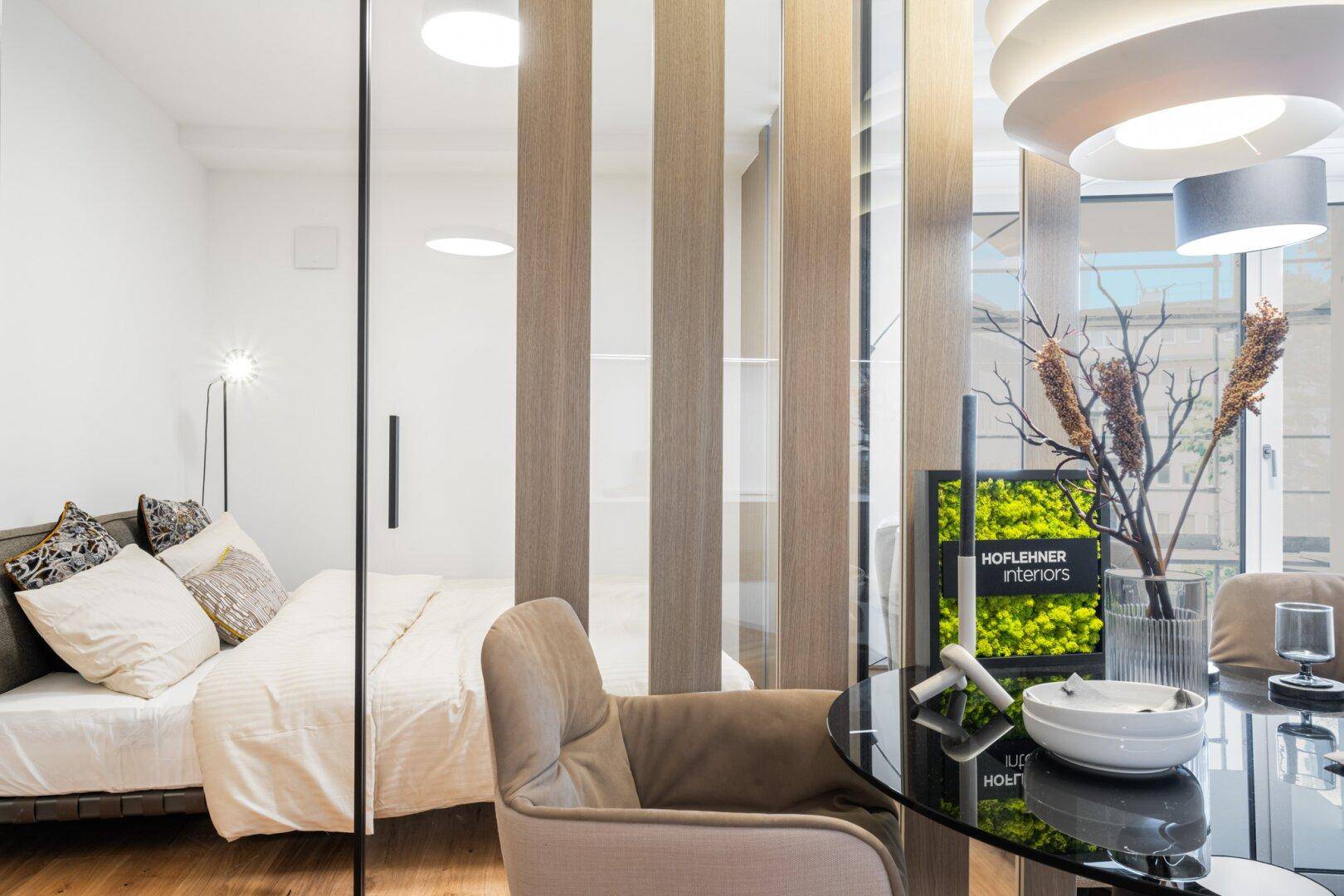 Helles Schlafzimmer mit Holzboden und moderner Raumtrennung zum Wohnbereich.