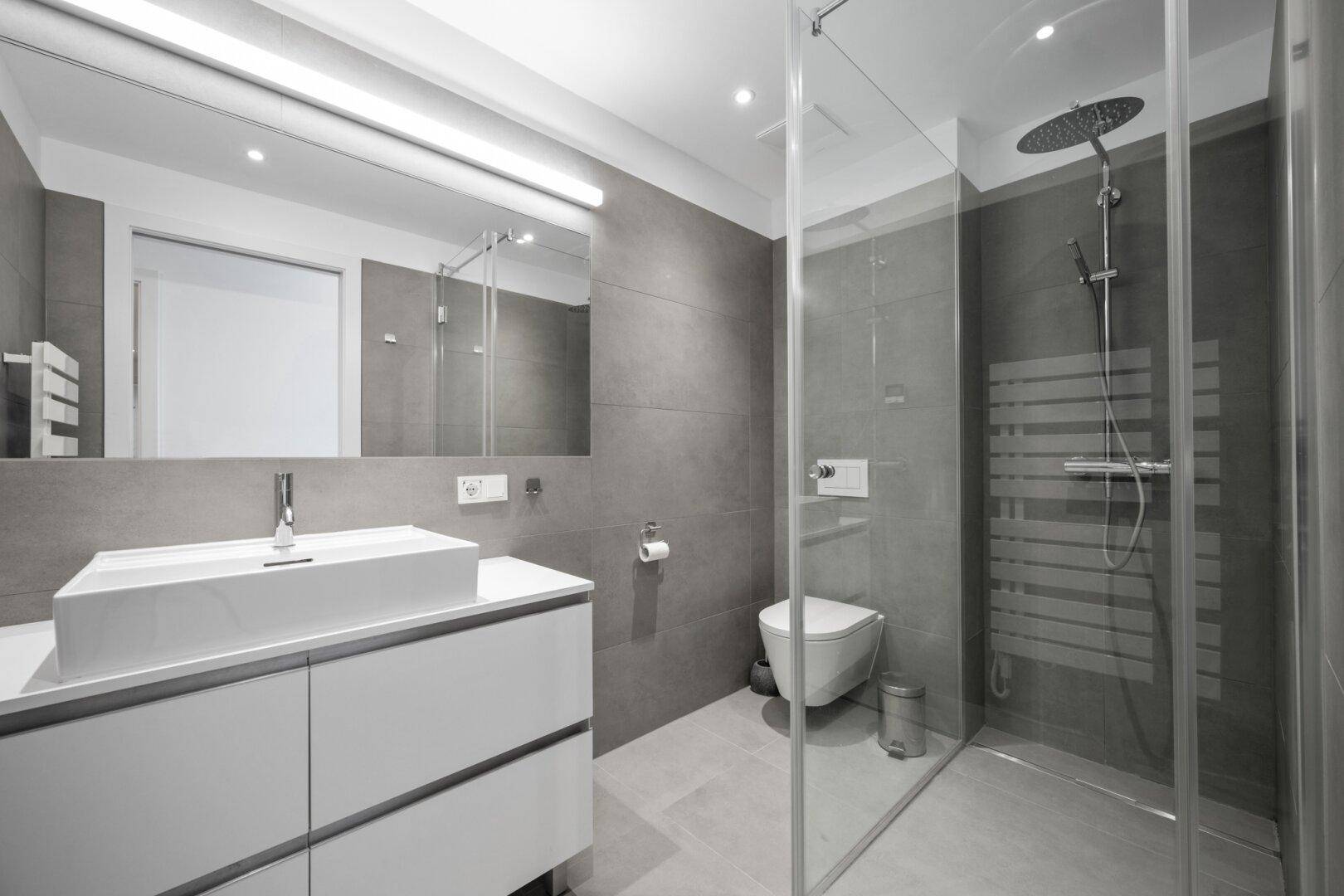 Modernes Badezimmer mit großer begehbarer Dusche, Waschtisch und Wand-WC.