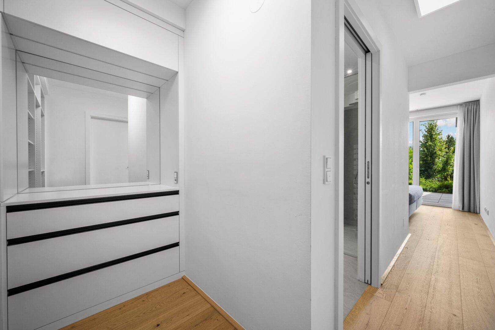 Heller Flur mit integriertem Schrank und Blick auf das Schlafzimmer mit Terrasse.