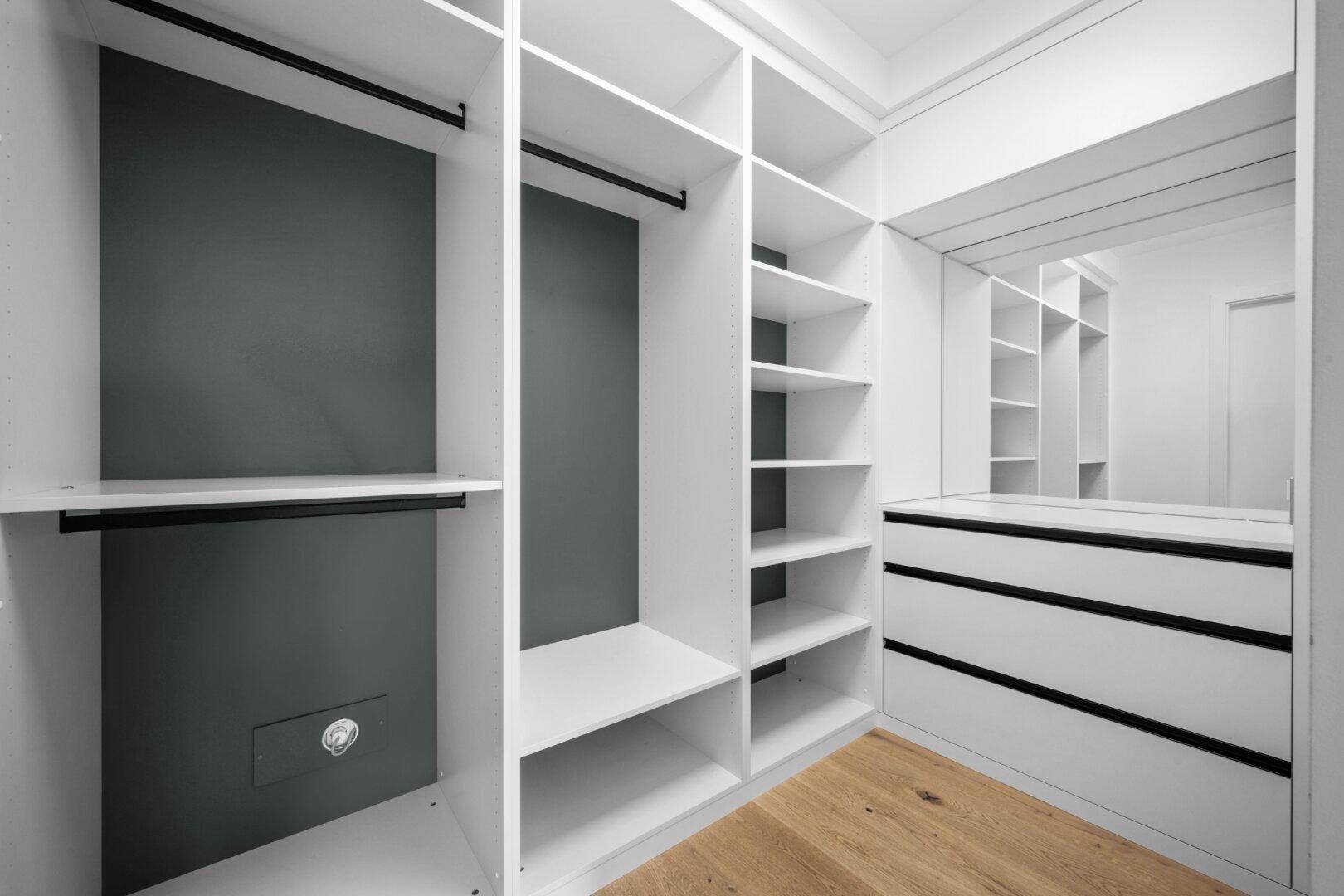 Geräumiger begehbarer Kleiderschrank mit Regalen, Schubladen und Kleiderstangen.