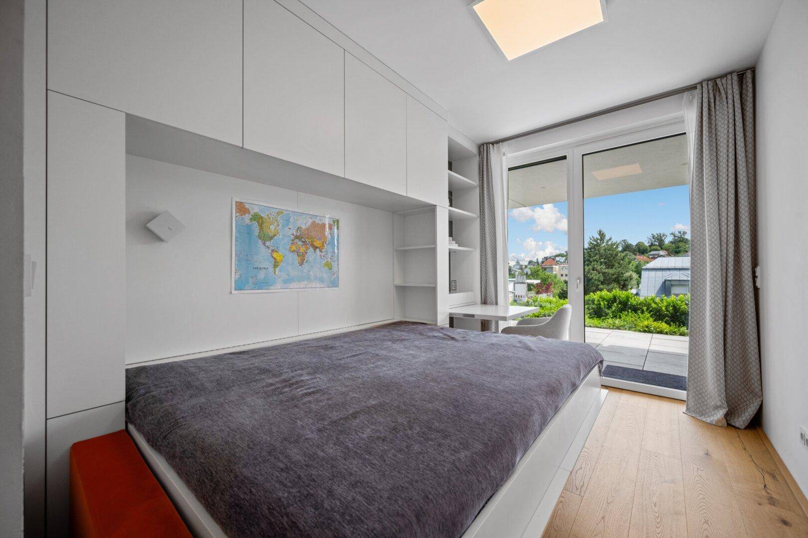 Helles Schlafzimmer mit integriertem Schreibtisch, Stauraum und Terrassenzugang.
