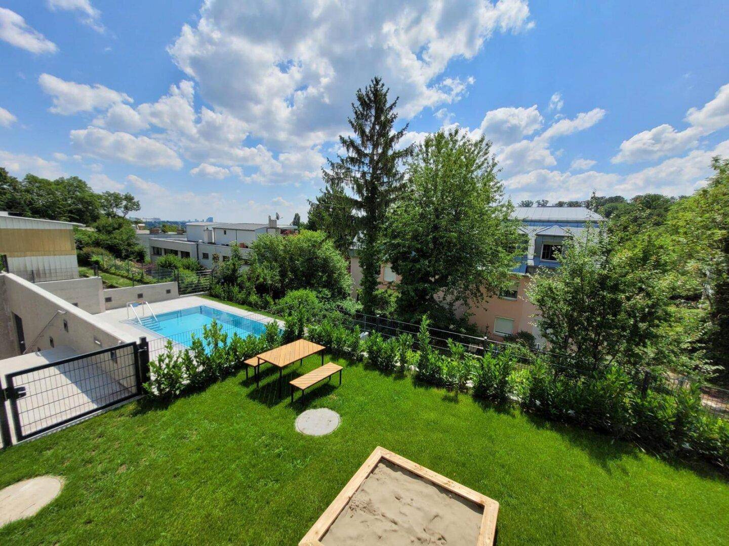 Großer Gartenbereich mit Pool, Sandkasten und Sitzgelegenheiten im Freien.