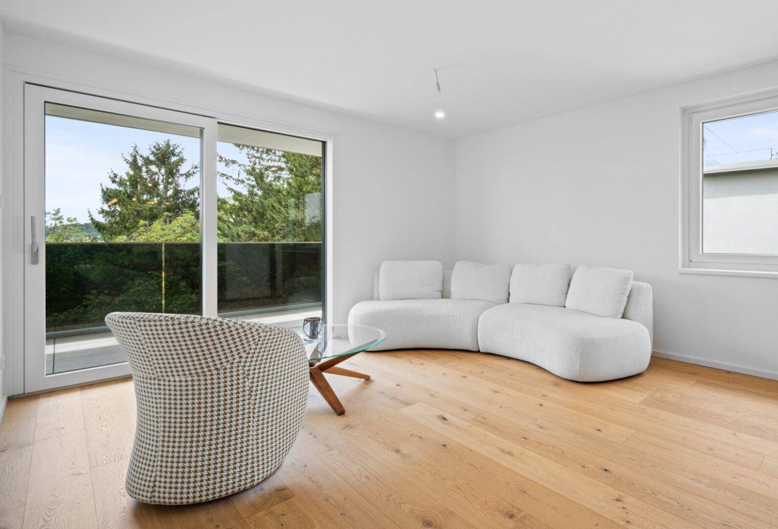 Helles Wohnzimmer mit modernem Sofa, Holzboden und Zugang zum Balkon.
