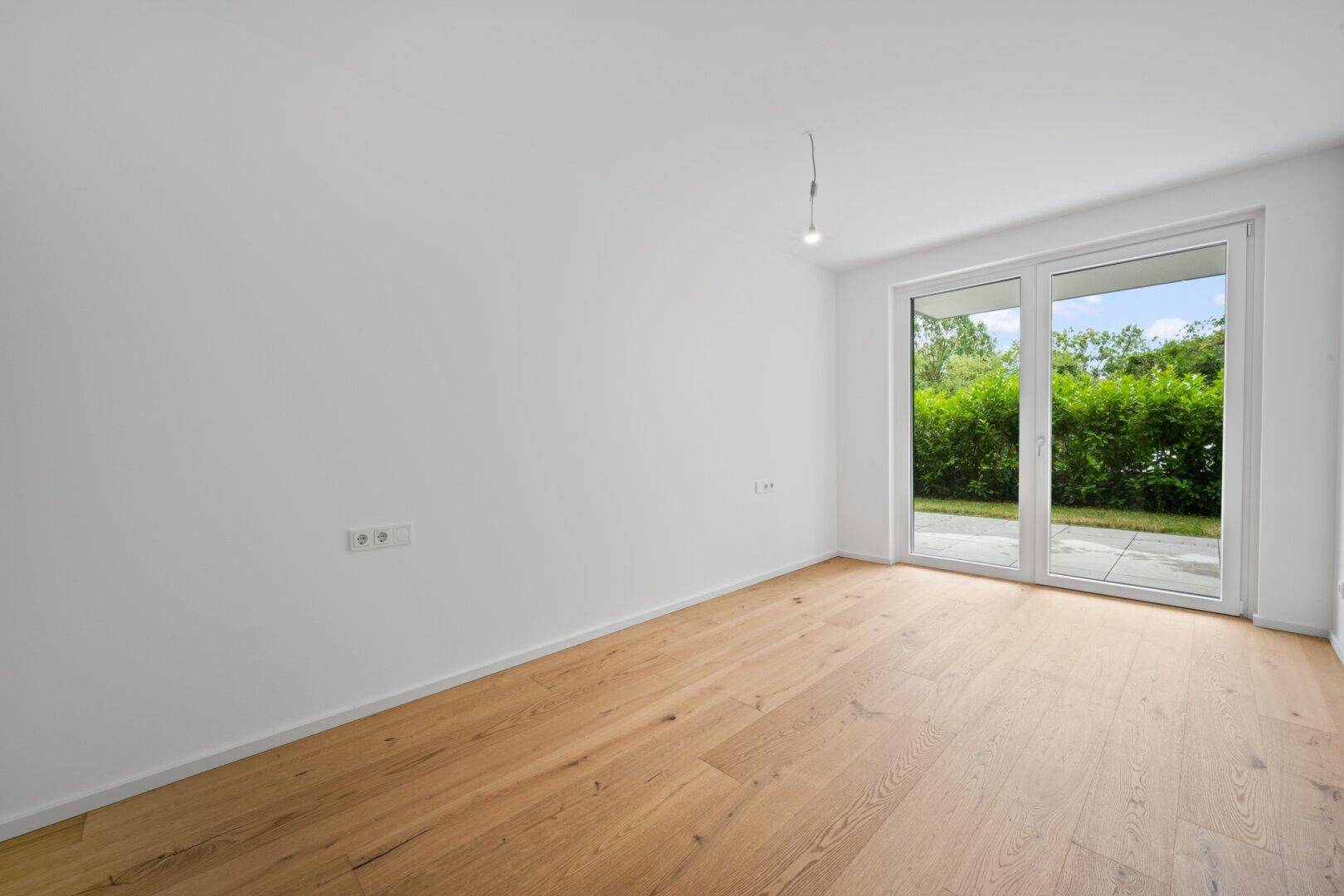 Helles Zimmer mit Holzboden und direktem Zugang zum grünen Gartenbereich.