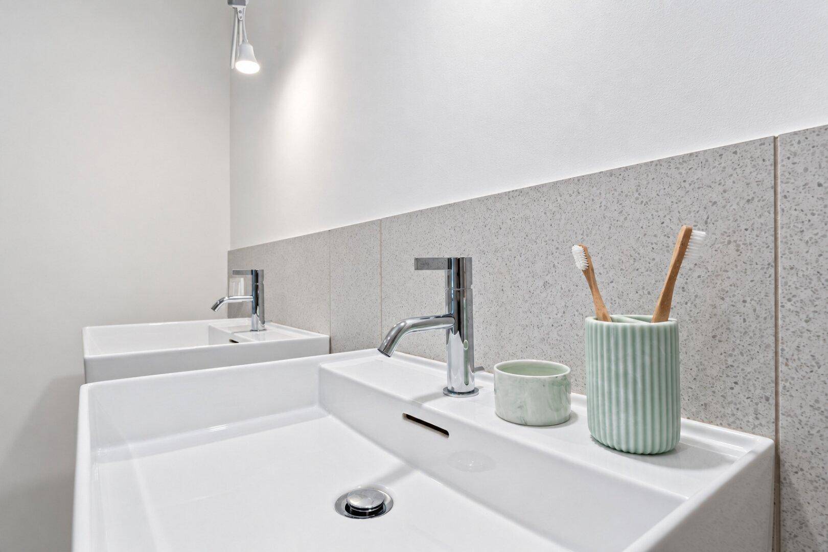 Detailansicht von zwei modernen Waschbecken mit Chromarmaturen in einem hellen Badezimmer.