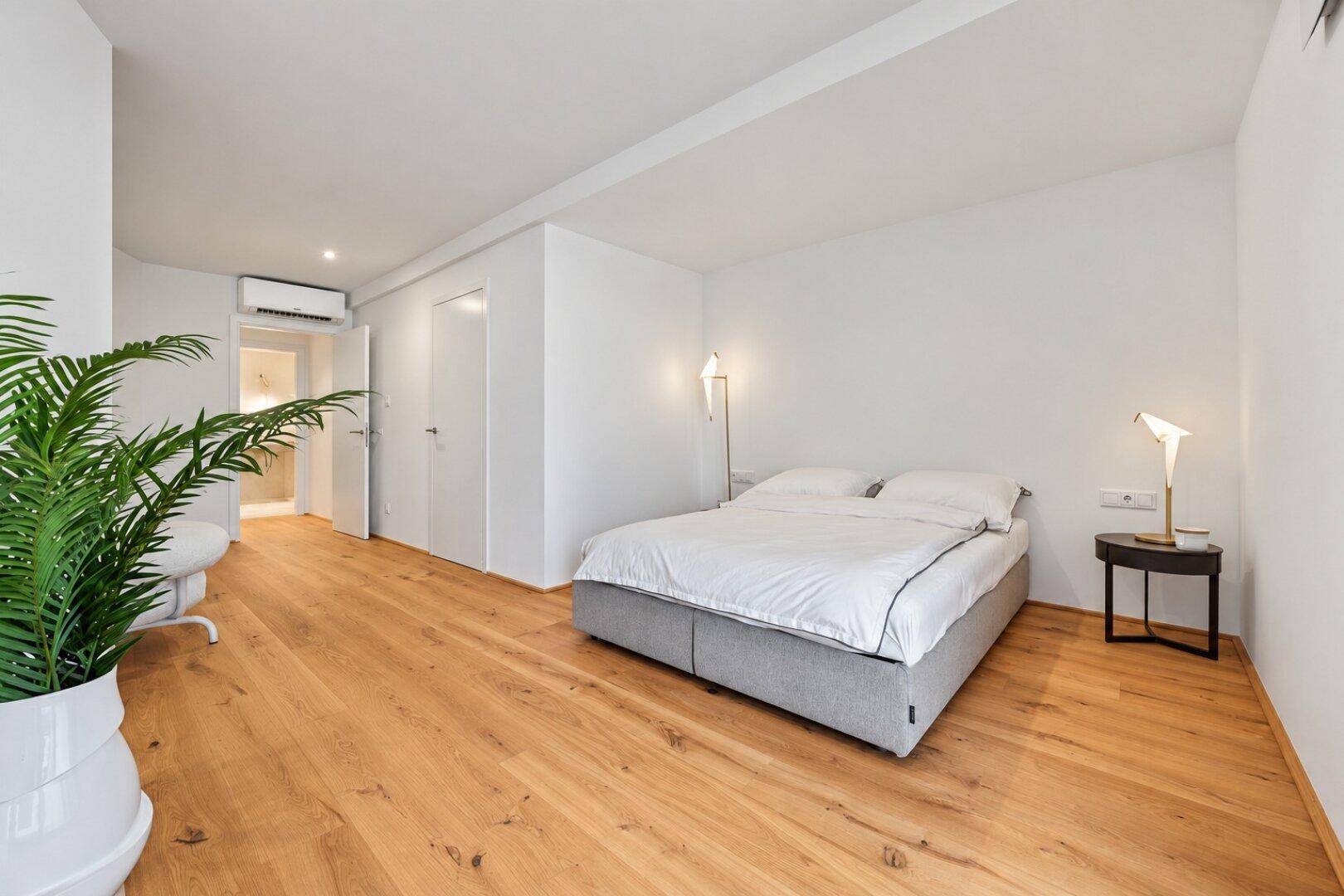 Modernes Schlafzimmer mit Holzboden, Klimaanlage und minimalistischer Einrichtung.