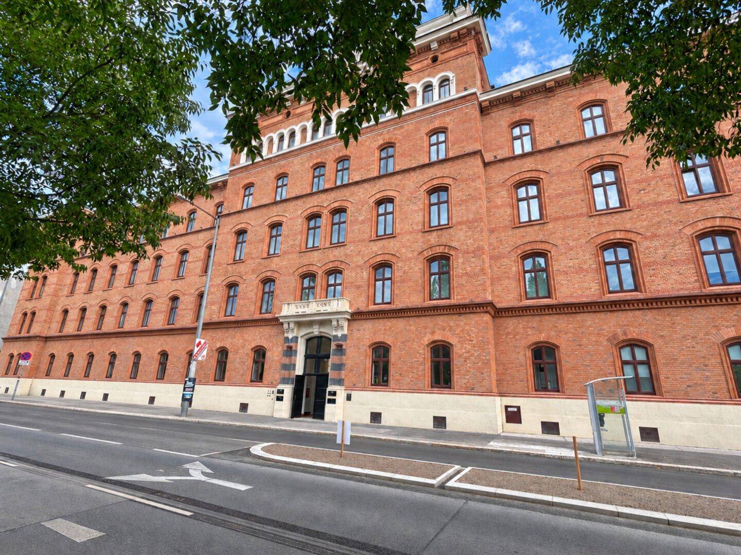 Historisches Backsteingebäude mit markanter Fassade und vielen Fenstern entlang einer Straße.