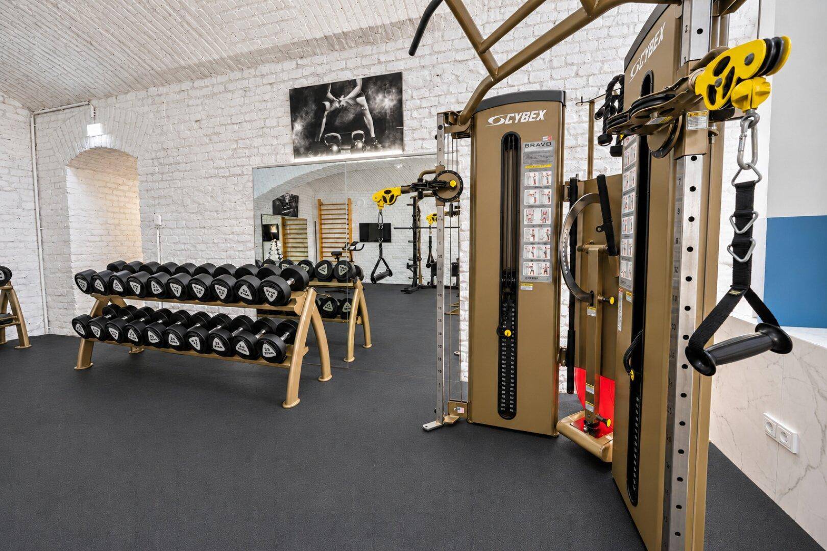 Gut ausgestatteter Fitnessraum mit verschiedenen Trainingsgeräten und Hanteln.