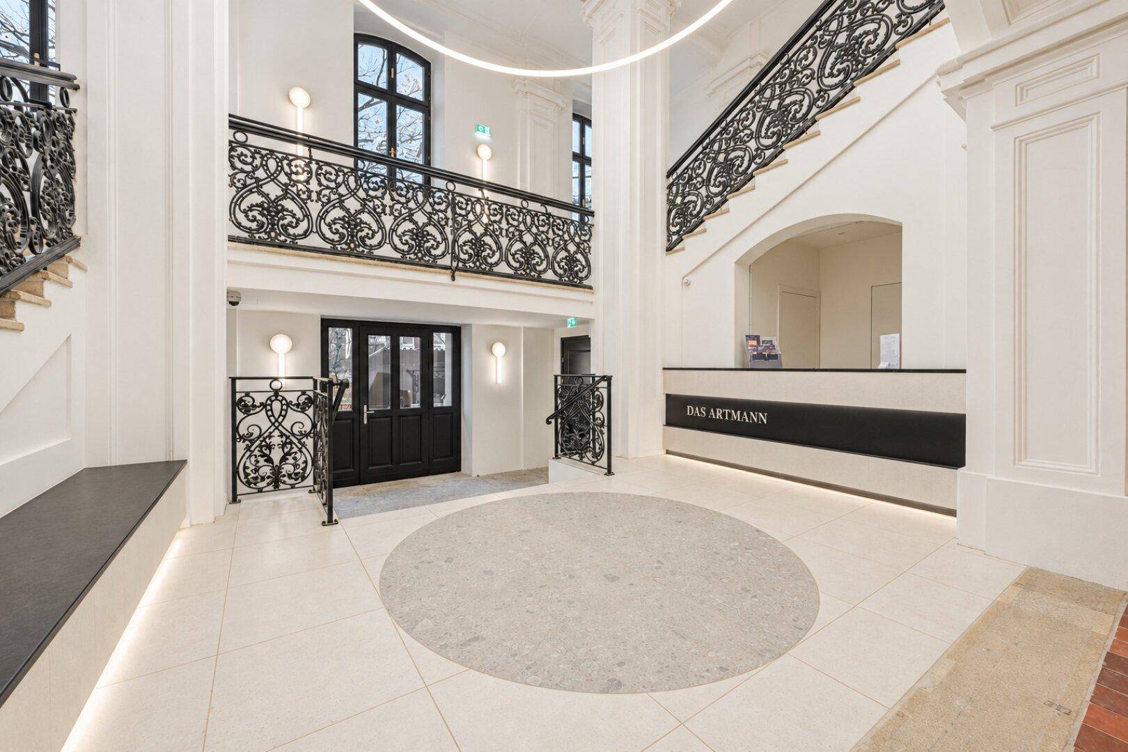Elegante Eingangshalle mit geschwungener Treppe, kunstvollen Geländern und hohen Decken.