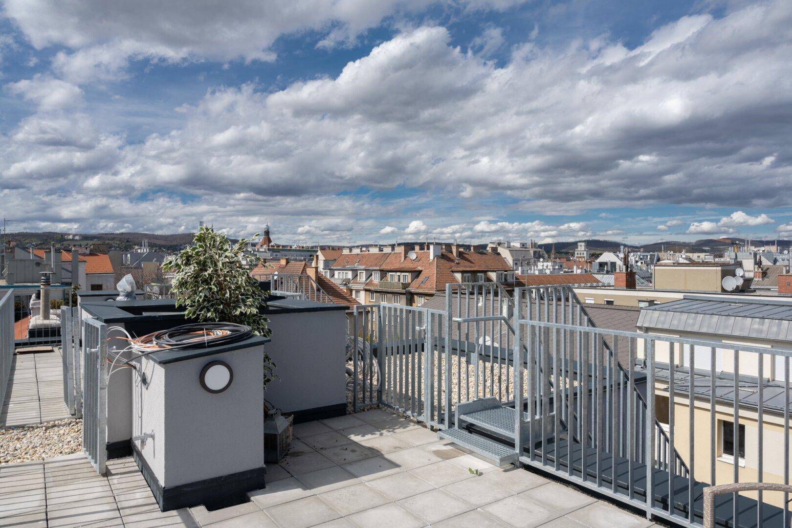 Weitläufige Dachterrasse mit Blick auf die Stadt und umliegende Gebäude.