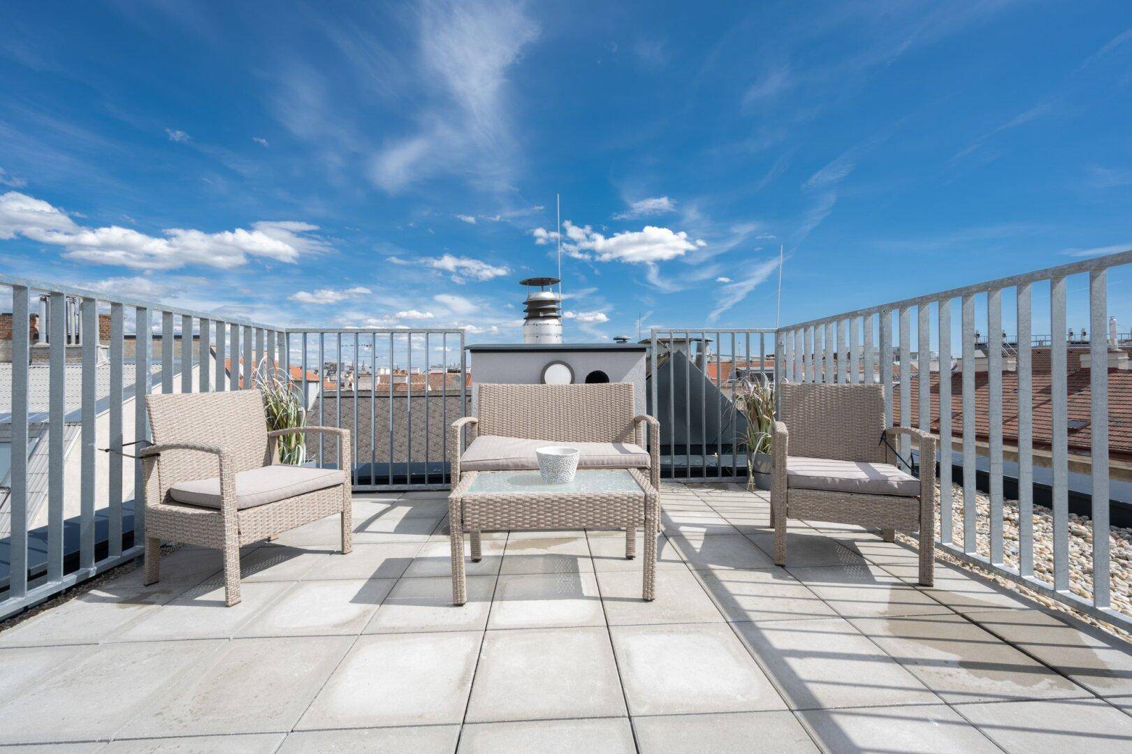 Sonnige Dachterrasse mit bequemen Sitzgelegenheiten und Panoramablick über die Dächer der Stadt.