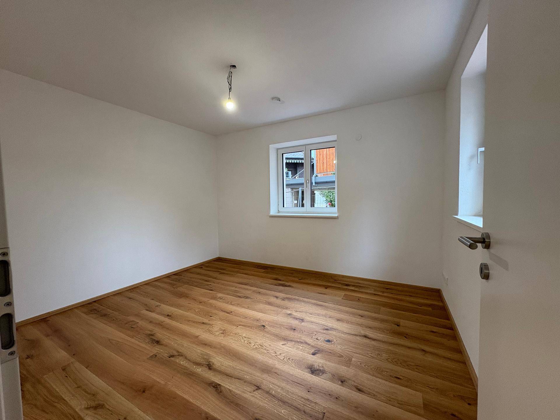 Helles Schlafzimmer mit Eichenparkettboden und Fenster, bereit zur Einrichtung.