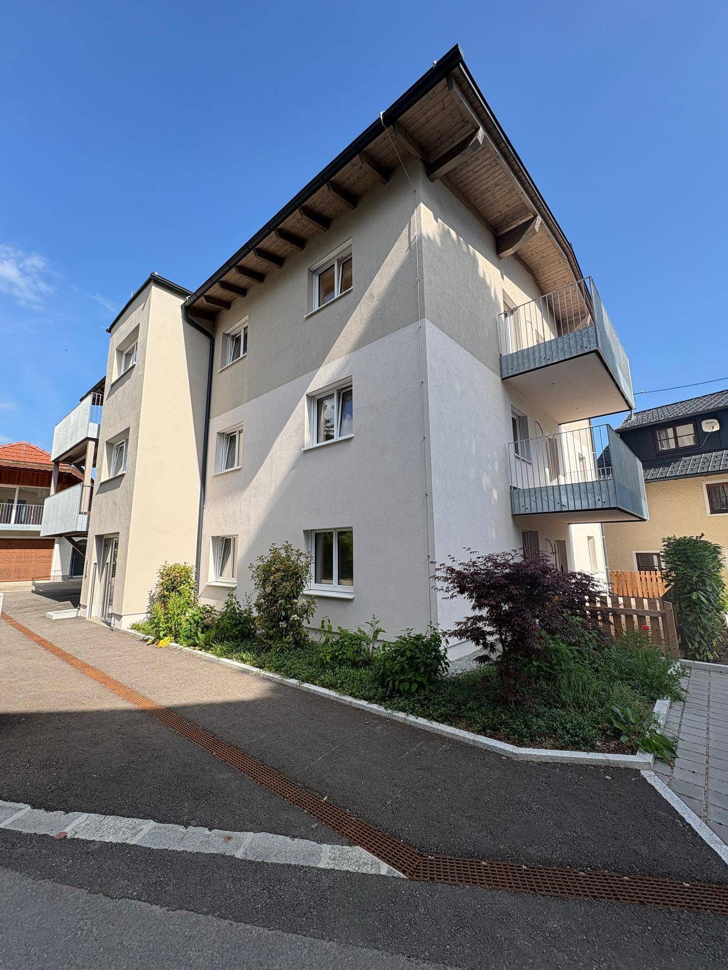 Ansicht des modernen Wohnhauses mit mehreren Balkonen und gepflegter Außenanlage bei Sonnenschein.