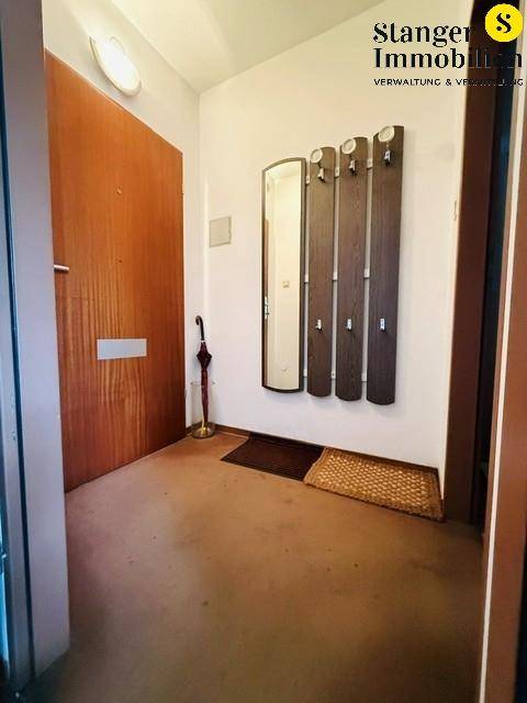 Eingangsbereich mit Holztür, Garderobe und Spiegel, einladend und funktional.