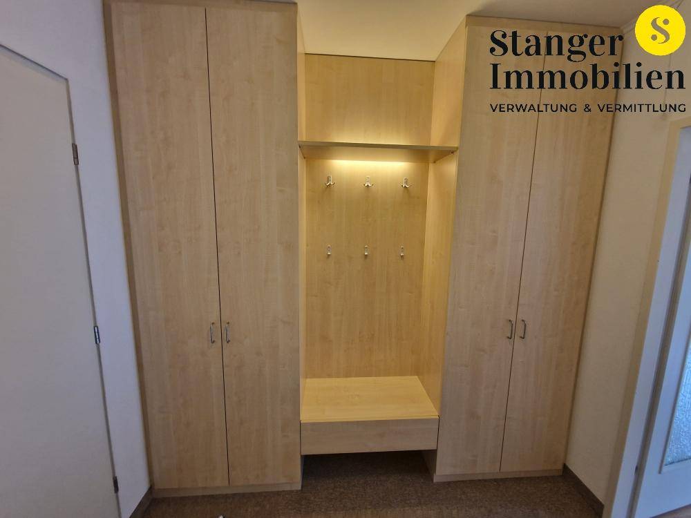 Detaillierte Ansicht der maßgefertigten Garderobe im Flur mit integrierter Sitzbank und Beleuchtung.