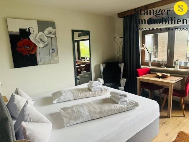 Gemütliches Schlafzimmer mit Doppelbett, kleinem Essbereich und moderner Kunst an den Wänden.