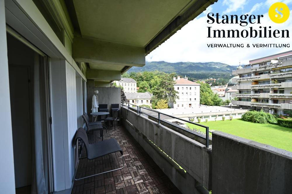 Möblierter Balkon mit Holzboden und einem malerischen Blick auf die Berge und die Stadt.